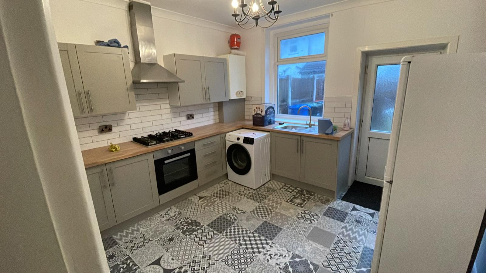 Refurbished grey shaker kitchen with oak worktops and patterned floor